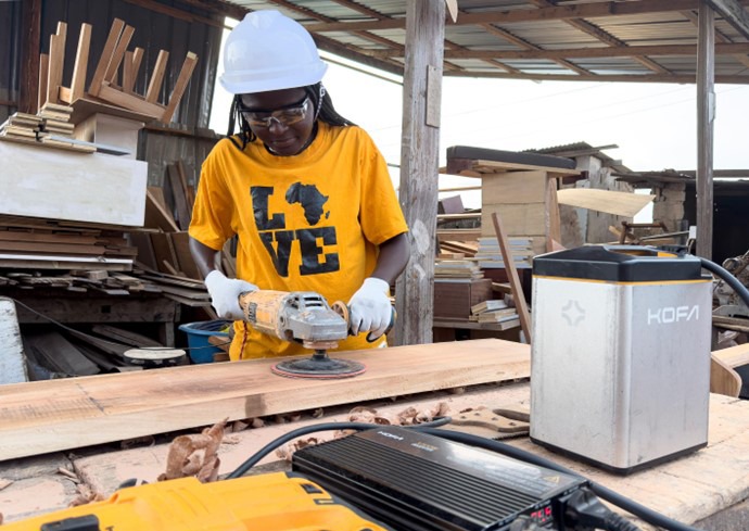 Small business worker using a sander powered by KofaGo portable battery in Ghana